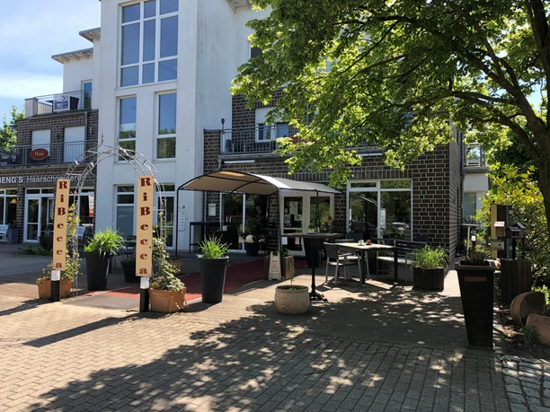 The RiBecca Hotel with modern architecture, an inviting entrance area and green planting.