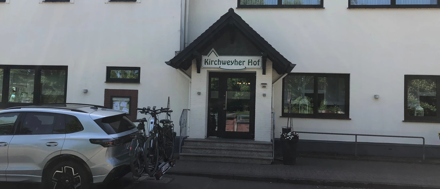 Kirchweyher Hof Eingangsbereich eines Hotels mit einem Schild "Kirchweyher Hof" über der Tür, Fahrradträger auf Auto.