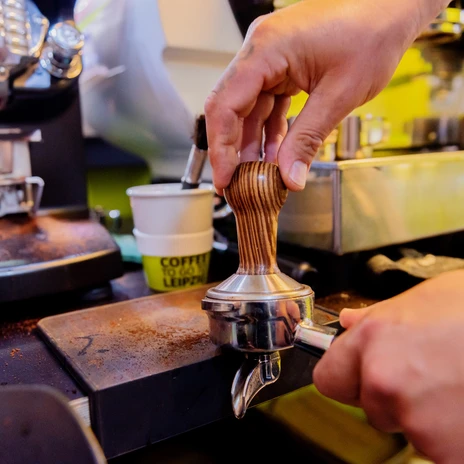 Coffee Enjoyment at IMEX 2022 | Leipzig Convention Bureau Pressing coffee grounds into the portafilter at IMEX 2022 - presented by Leipzig Convention Bureau