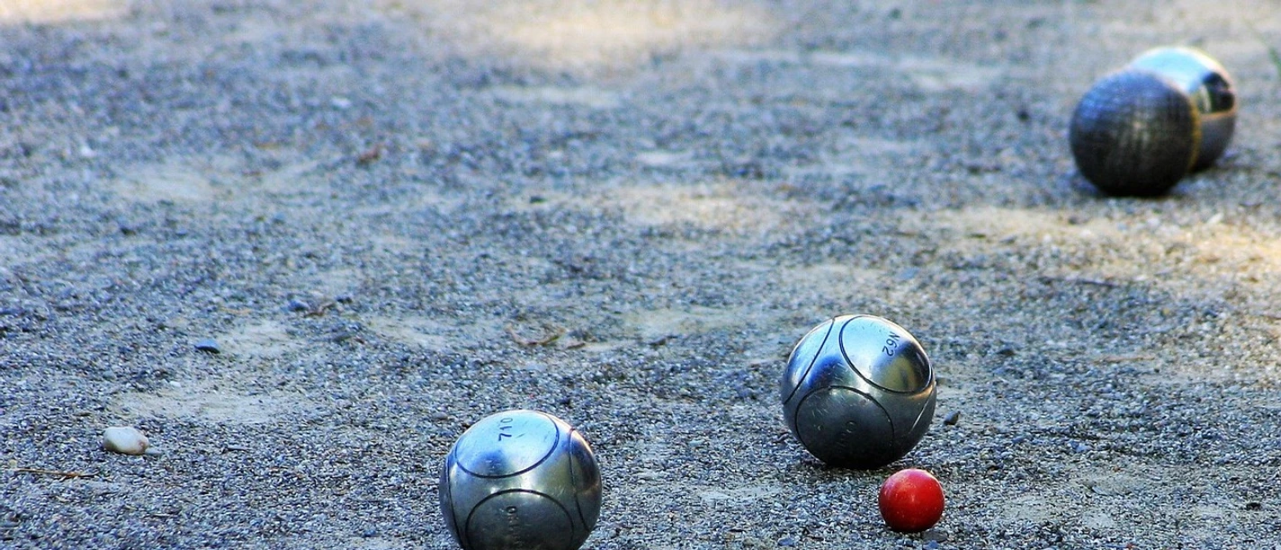 Boulefeld Mehrere Boulekugeln liegen verstreut auf einem sandigen Spielfeld unter freiem Himmel.