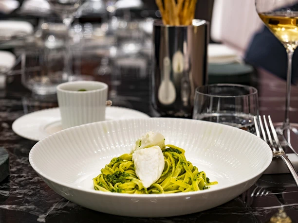 OTTO für dich An elegant plate of pasta with green sauce and mozzarella set against a stylishly arranged table.