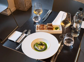 maiBeck Fein gedeckter Tisch im maiBeck mit elegant angerichteter Vorspeise und Getränken üppig.Exquisitely set table at maiBeck restaurant, abundantly featuring an elegantly presented appetizer accompanied by beverages.