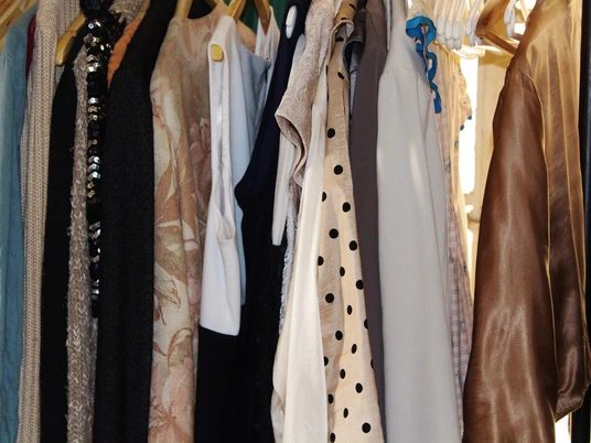 Kleiderstange Flohamrkt Kleider unterschiedlicher Stile und Farben hängen auf einer Flohmarktstange dicht nebeneinander.