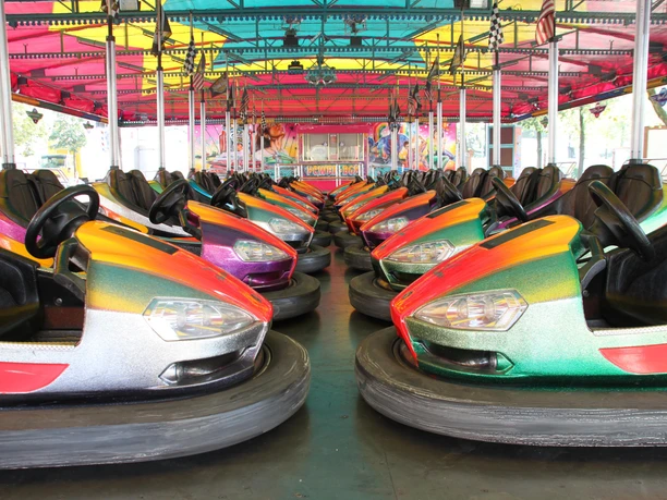 City-Fest in Espelkamp Bunte Autoscooter mit leuchtenden Farben stehen in zwei Reihen unter einem farbenfrohen Dach.
