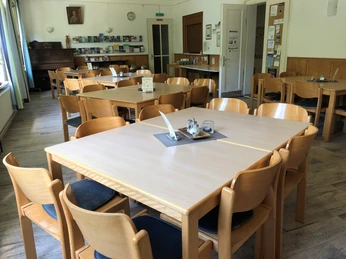 Speisesaal Heller Speisesaal mit Holzstühlen und Tischen, dekoriert mit Informationsbroschüren und Bildern an den Wänden.