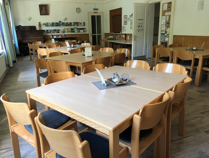 Speisesaal Heller Speisesaal mit Holzstühlen und Tischen, dekoriert mit Informationsbroschüren und Bildern an den Wänden.Bright dining room with wooden chairs and tables, decorated with information brochures and pictures on the walls.Lys spisestue med træstole og -borde, dekoreret med informationsbrochurer og billeder på væggene.Lichte eetzaal met houten stoelen en tafels, gedecoreerd met informatiebrochures en foto's aan de muren.