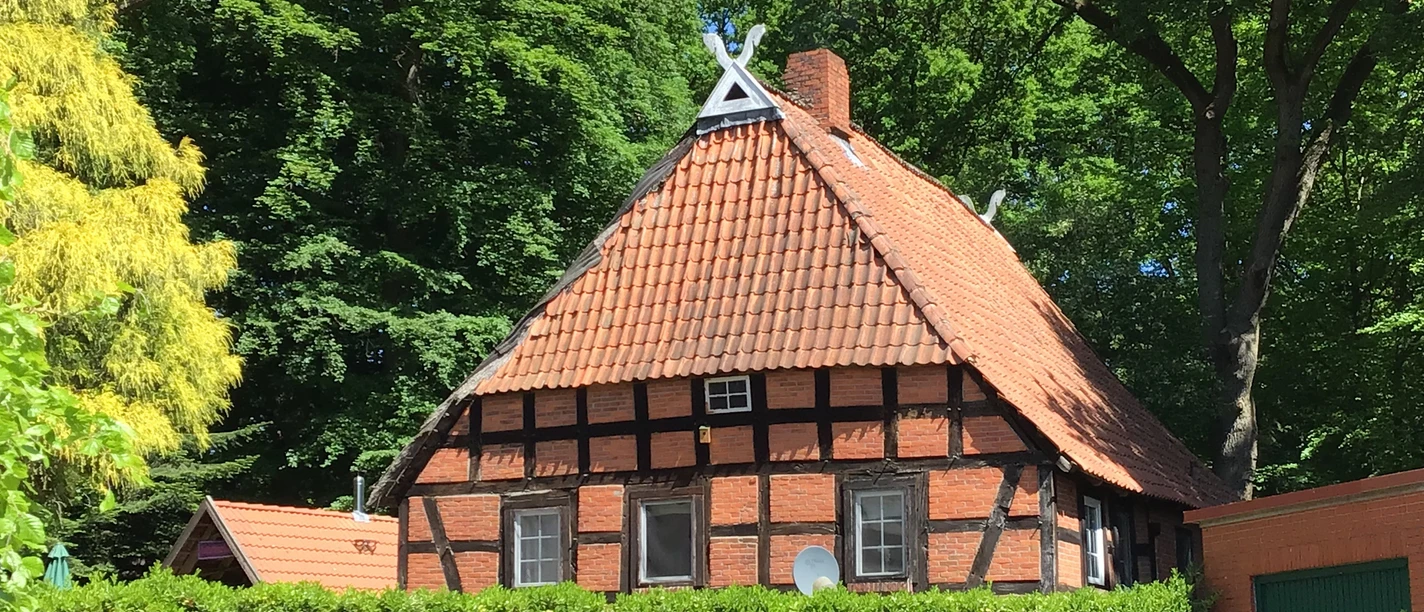 Müllers Alte Kate Ein traditionelles Fachwerkhaus mit rotem Ziegeldach umgeben von üppigem Grün in ländlicher Kulisse.