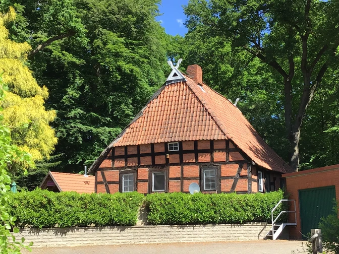 Müllers Alte Kate Ein traditionelles Fachwerkhaus mit rotem Ziegeldach umgeben von üppigem Grün in ländlicher Kulisse.