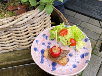 Snack in der Weinbar1775-Pro Herford GmbH.jpg Bunter Teller mit rustikalem Brot, Rindfleisch, Kirschtomate und Blattsalat, serviert auf einer Terrasse.