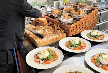 Kulinarische Führung_Elsbach-Restaurant-Pro Herford GmbH.jpg Ein Kellner richtet in einer Restaurantküche auf Tellern präzise angerichtete Speisen an.