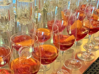 Aperitif-Kulinarische Führung-Pro Herford GmbH.jpg Gläser voller Aperol-Spritz stehen aufgereiht auf einem Tisch, bereit für eine kulinarische Veranstaltung.