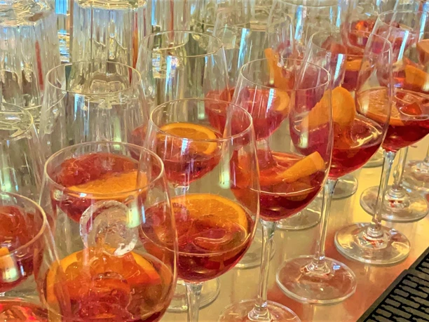 Aperitif-Kulinarische Führung-Pro Herford GmbH.jpg Gläser voller Aperol-Spritz stehen aufgereiht auf einem Tisch, bereit für eine kulinarische Veranstaltung.