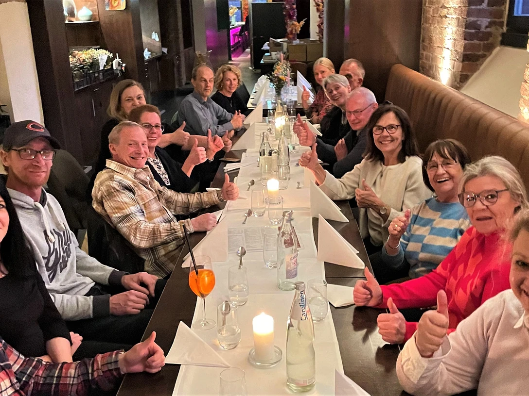 Gesellige Runde-Kulinarische Führung-Pro Herford GmbH.jpg Menschen sitzen an langer Tafel in einem Restaurant und lächeln, während sie die Atmosphäre genießen.