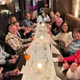 Gesellige Runde-Kulinarische Führung-Pro Herford GmbH.jpg Menschen sitzen an langer Tafel in einem Restaurant und lächeln, während sie die Atmosphäre genießen.