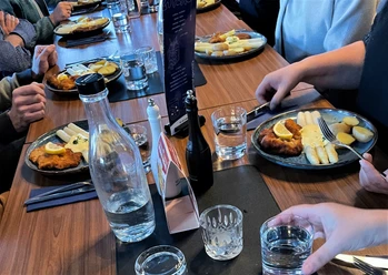 Hauptgang-Kulinarische Führung-Pro Herford GmbH.jpg Mehrere Personen sitzen an einem Tisch und genießen Teller mit Schnitzel, Spargel und Kartoffeln.