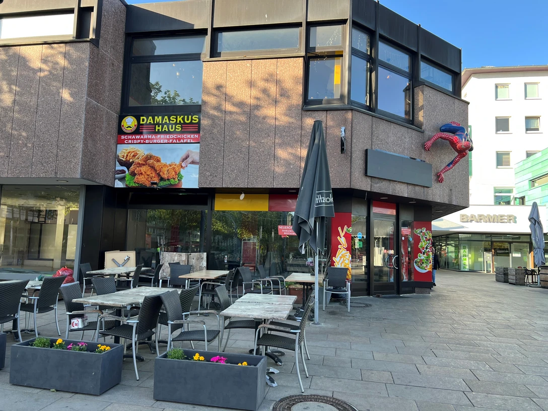 Damaskus Haus 2.jpg Ansicht auf ein modernes Restaurant mit einer Terrasse und einem auffälligen Superhelden an der Fassade.