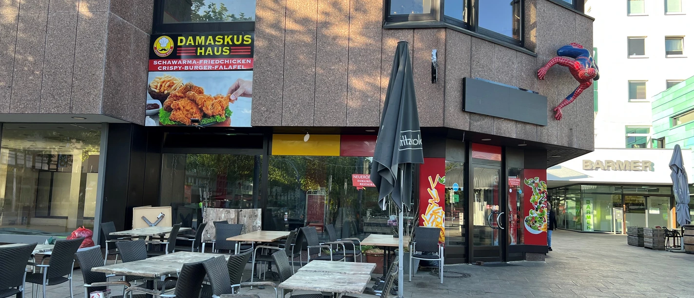 Damaskus Haus 2.jpg Ansicht auf ein modernes Restaurant mit einer Terrasse und einem auffälligen Superhelden an der Fassade.