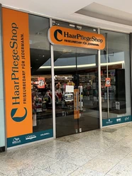 Haarpflegeshop.jpg Eingang eines Haarpflege-Shops mit Friseurbedarf und Markenlogos wie Wella, L'Oréal und Schwarzkopf.