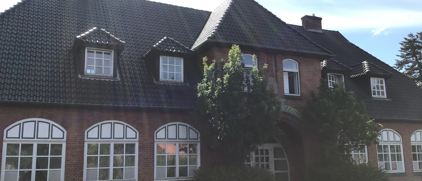 Hotel Pfeffermühle Historisches Backsteingebäude mit großen Sprossenfenstern und einem begrünten Eingangsbereich.