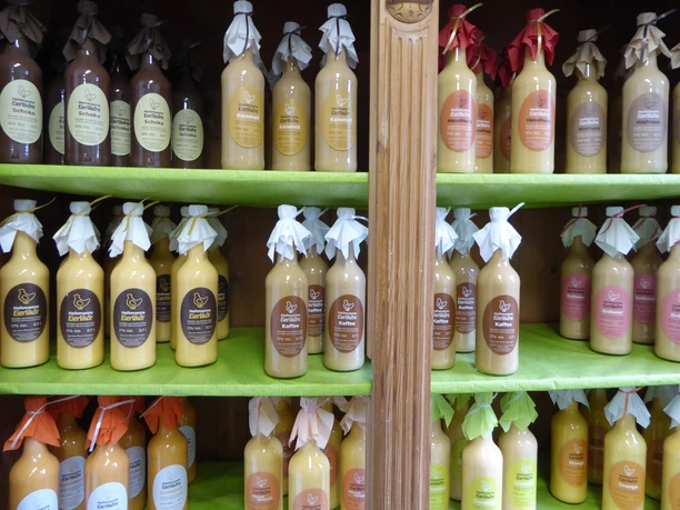 Regale voller bunter Likörflaschen mit dekorativen Schleifen, aufgereiht in einem Laden.