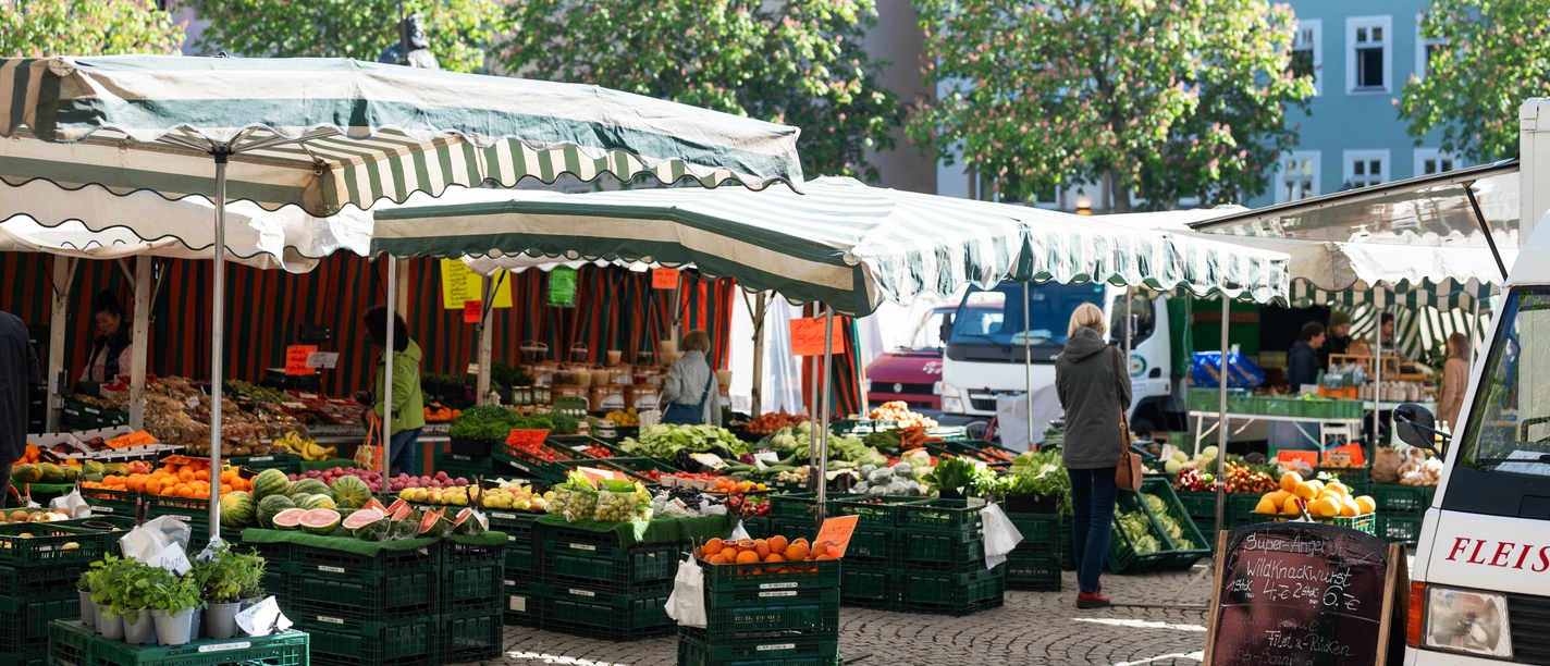 Jenaer Wochenmarkt Stand auf dem Jenaer Wochenmarkt mit Kisten voll Gemüse und Obst, dazwischen Kunden und ein Händler
