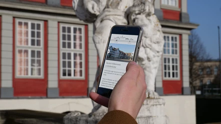 Digitale Stadtführung Smartphone in einer Hand, auf dem Display Informationen über Wolfenbüttel