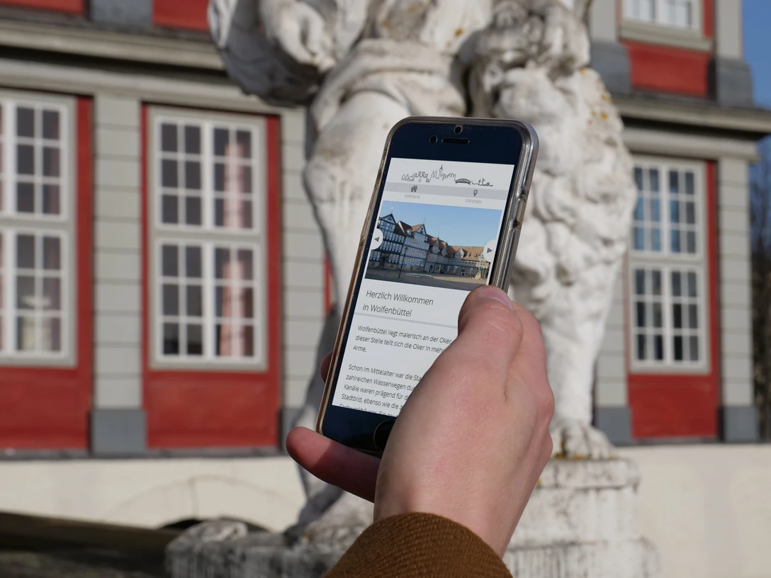 Digitale Stadtführung Smartphone in einer Hand, auf dem Display Informationen über Wolfenbüttel