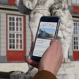 Digitale Stadtführung Smartphone in einer Hand, auf dem Display Informationen über Wolfenbüttel