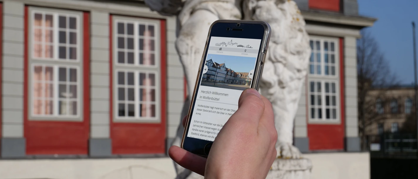 Digitale Stadtführung Smartphone in einer Hand, auf dem Display Informationen über Wolfenbüttel