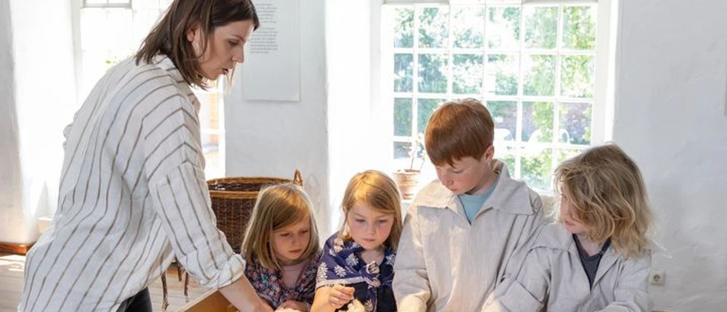 Familienführung im LVR-Industriemuseum Textilfabrik Cromford Eine Gruppe von Kindern erkundet Baumwolle mit einer Begleitperson im LVR-Industriemuseum.
