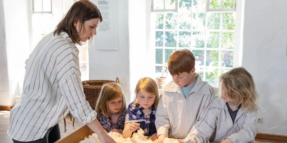 Familienführung im LVR-Industriemuseum Textilfabrik Cromford Eine Gruppe von Kindern erkundet Baumwolle mit einer Begleitperson im LVR-Industriemuseum.