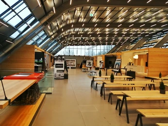 Herford-Bora Flagshipstore_Pro Herford GmbH (4).jpeg Moderner Innenraum eines Showrooms mit Holztischen, Kochinsel und großen Fenstern.