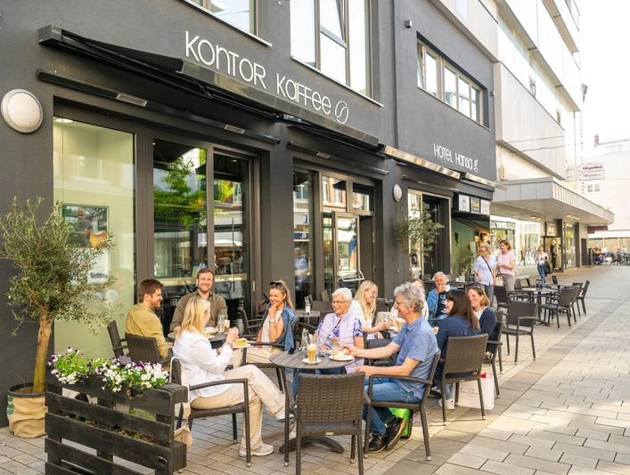 Herford-2025-229-©Teutoburger Wald - Pro Herford GmbH - D. Ketz.jpg Menschen genießen Kaffee und Gespräche auf der Terrasse vor dem Café Kontor in Herford.