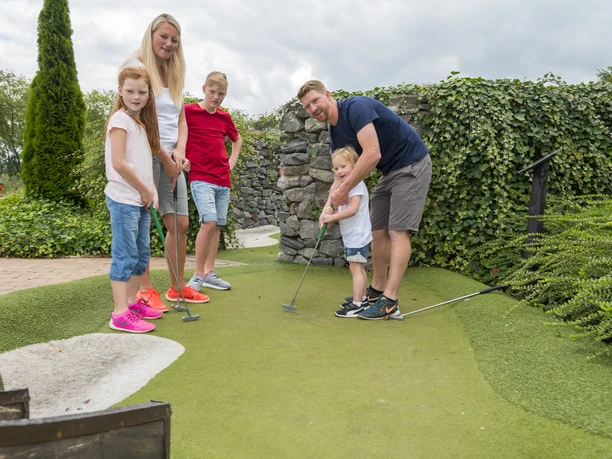 Adventure Golf im Freizeitpark von Schloss Dankern - Familienurlaub im Emsland ©Emsland Tourismus GmbH (5).jpg Familie spielt gemeinsam Adventure Golf zwischen Steinmauern und Grünflächen im Freizeitpark.