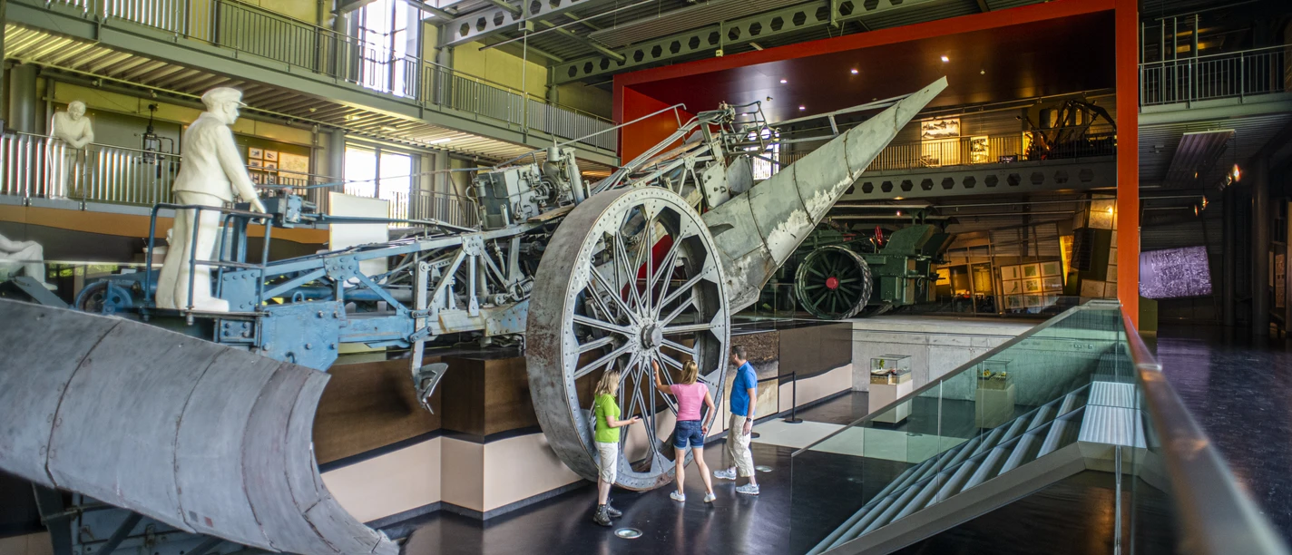 Emsland Moormuseum in Geeste – Mammut in Ausstellungshalle II ©TMN GmbH, Sabine Braun Fotografie-365.jpg Besucher betrachten eine große historische Torfabbau-Maschine im Emsland Moormuseum in Geeste.