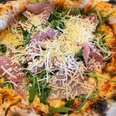 Pizza-Pro Herford GmbH.jpg Frisch gebackene Pizza mit knusprigem Rand, belegt mit Rucola, Parmaschinken und frischem Parmesan.