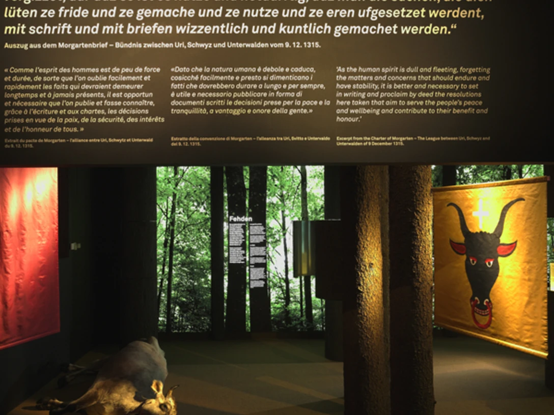 Bild aus der Ausstellung Eine Kuhl liegt auf dem Boden zwischen Baumstämmen