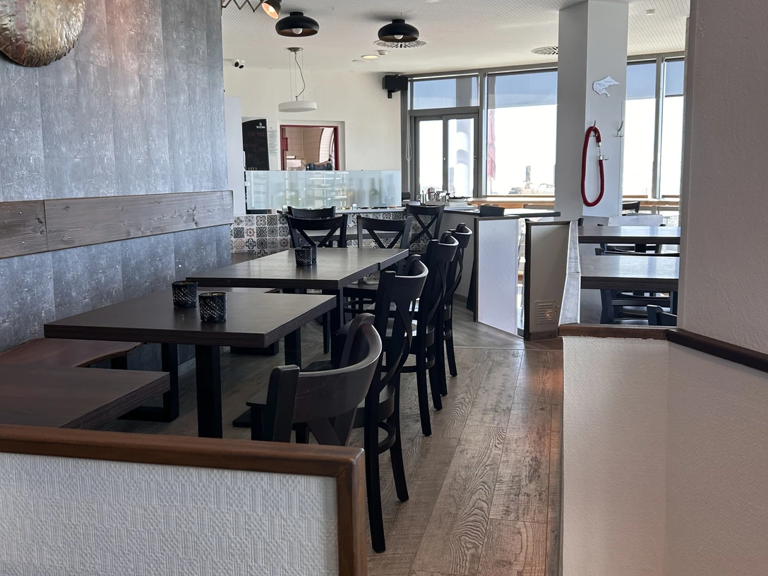 Ein einladendes, modernes Restaurant mit Holzboden, stilvollen dunklen Möbeln und viel Tageslicht.An inviting, modern restaurant with wooden floors, stylish dark furniture and plenty of natural light.