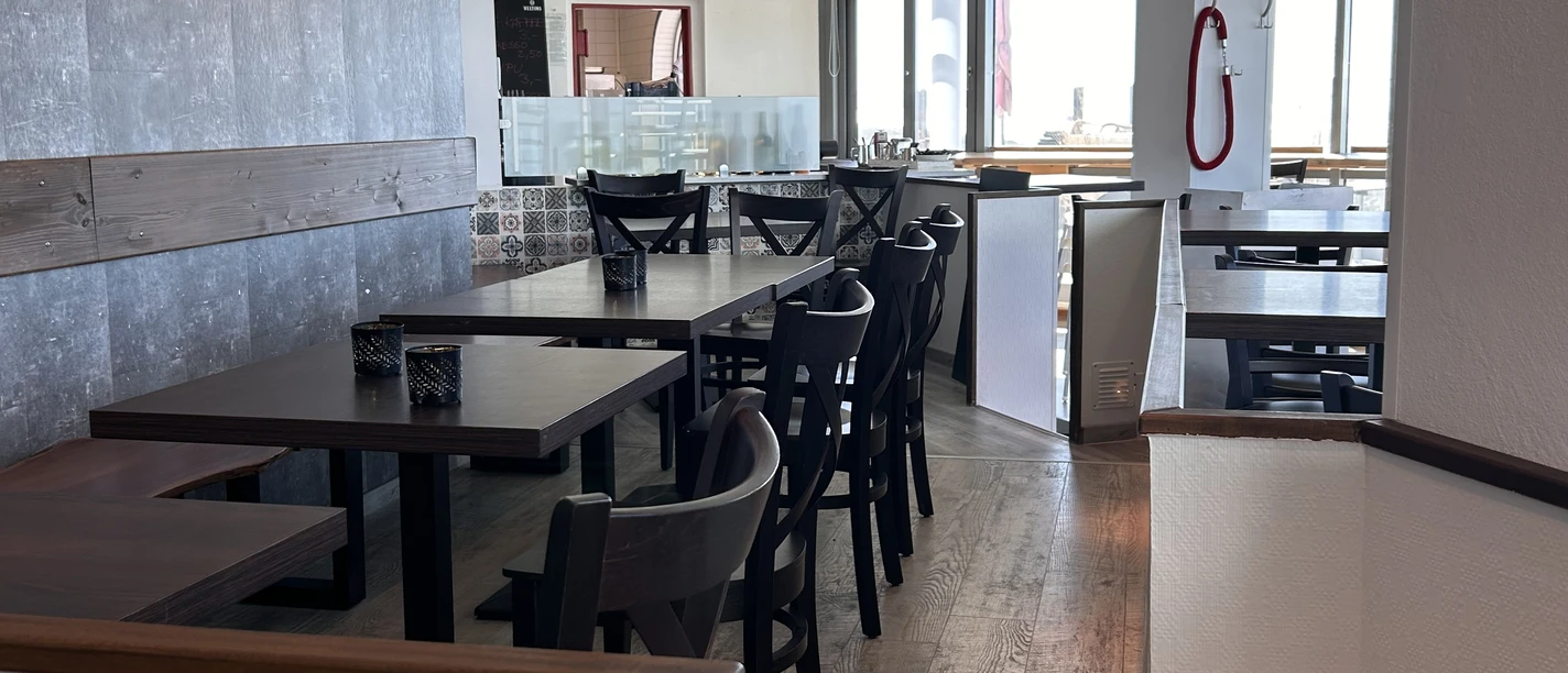 image00005.jpeg Ein einladendes, modernes Restaurant mit Holzboden, stilvollen dunklen Möbeln und viel Tageslicht.