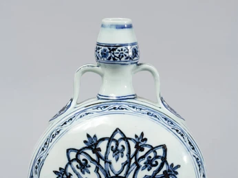 Moon bottle Eine kunstvoll verzierte Porzellan-Flasche mit runden Formen und blauen floralen Mustern auf weißem Grund.An artfully decorated porcelain bottle with round shapes and blue floral patterns on a white background.