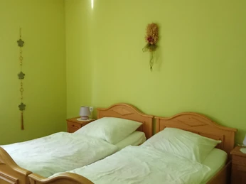 Schlafzimmer mit Holzbetten und hellgrünen Wänden