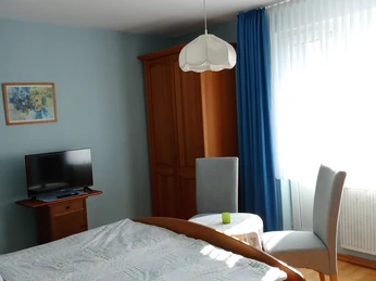 Schlafzimmer mit Holzbett, hellblaue Wände und blaue Vorhänge