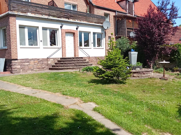 Außenansicht Backsteinhaus mit weißem Anbau und Garten