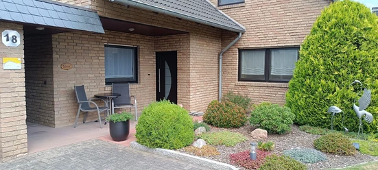 Hausansicht mit Terrasse der Ferienwohnung Peter Kliesch Elegantes Klinkerhaus mit separatem Zugang zur Ferienwohnung und Terrasse. Zwei Hochlehner sowie Bistrotisch im Außenbereich.