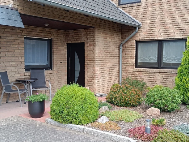 Hausansicht mit Terrasse der Ferienwohnung Peter Kliesch Elegantes Klinkerhaus mit separatem Zugang zur Ferienwohnung und Terrasse. Zwei Hochlehner sowie Bistrotisch im Außenbereich.