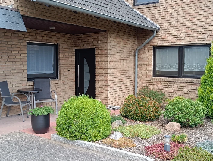 Hausansicht mit Terrasse der Ferienwohnung Peter Kliesch Elegantes Klinkerhaus mit separatem Zugang zur Ferienwohnung und Terrasse. Zwei Hochlehner sowie Bistrotisch im Außenbereich.