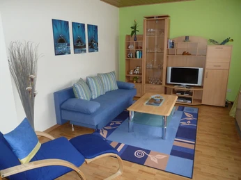 Wohnzimmer der Ferienwohnung Peter Kliesch Wohnzimmer der Ferienwohnung ,gemütliches Ambiente mit blauem Sofa, Holzschrankwand und Liegestuhl.