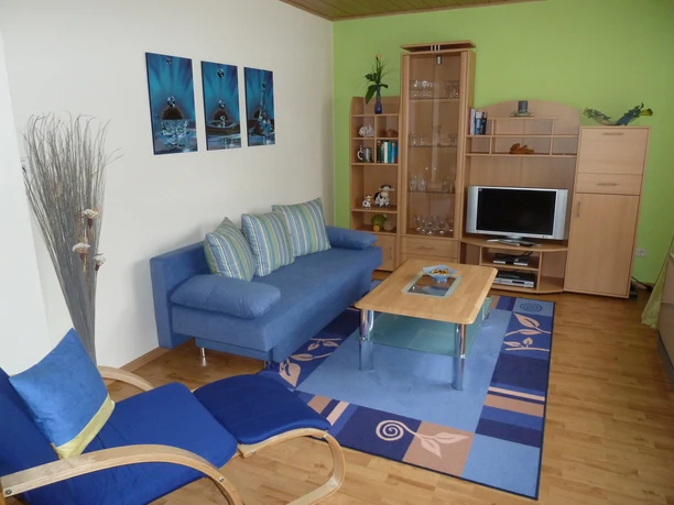 Wohnzimmer der Ferienwohnung Peter Kliesch Wohnzimmer der Ferienwohnung ,gemütliches Ambiente mit blauem Sofa, Holzschrankwand und Liegestuhl.