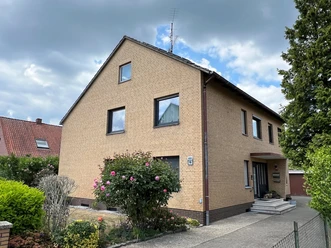 FeWo Gerth Gemütliches zweistöckiges Backsteinhaus mit gepflegtem Vorgarten, umgeben von hohen Bäumen.