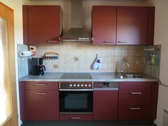 Küche der Ferienwohnung Peter Kliesch Küche in Bordeauxrot mit praktischer Ausstattung, inklusive Hängeschränken und Herd Ceranfeld.